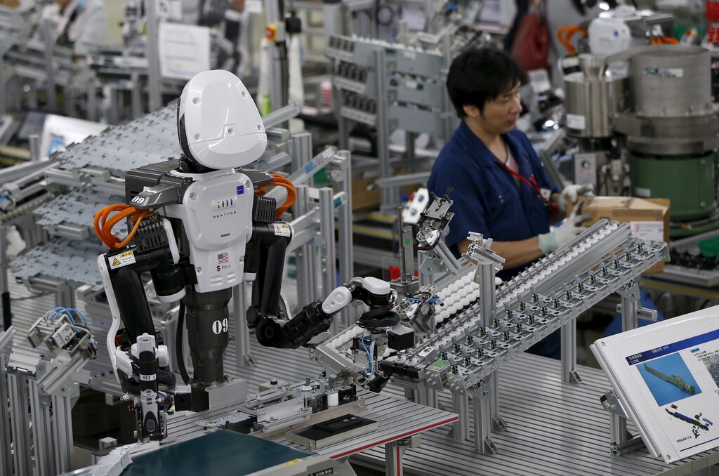 A humanoid robot works side by side with employees in the assembly line at a factory of Glory Ltd., a manufacturer of automatic change dispensers, in Kazo, north of Tokyo, Japan, July 1, 2015. Japanese firms are ramping up spending on robotics and automation, responding at last to premier Shinzo Abe's efforts to stimulate the economy and end two decades of stagnation and deflation. Picture taken July 1, 2015. REUTERS/Issei Kato - GF10000147193
