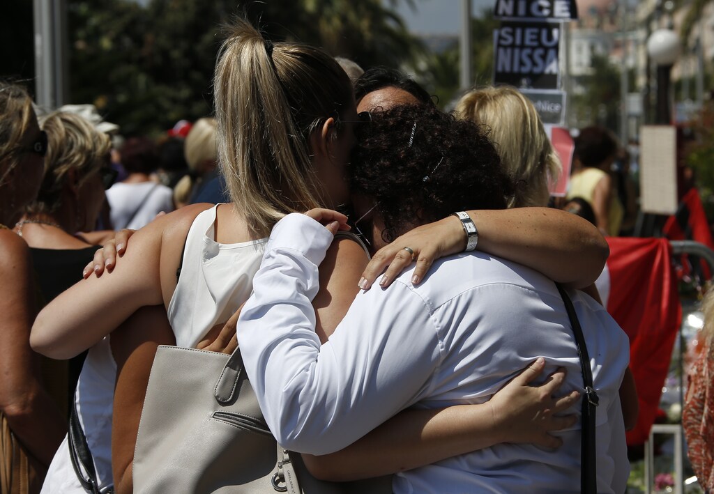 People hug on the Promenade des Anglais during a minute of silence on the third day of national mourning to pay tribute to victims of the truck attack along the Promenade des Anglais on Bastille Day that killed scores and injured as many in Nice, France, July 18, 2016. REUTERS/Eric Gaillard - LR1EC7I0T5EIM