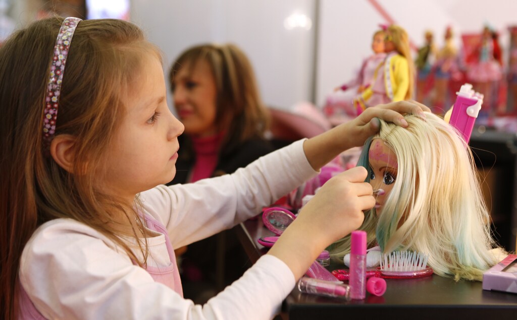 A young girl paints the face of a doll by the company Simba during the press preview of the 66th International Toy Fair in Nuremberg January 27, 2015. More than 2,700 exhibitors from over 60 countries worldwide will present their new toy products from January 28 to February 2, 2015. REUTERS/Michaela Rehle (GERMANY - Tags: SOCIETY BUSINESS) - GM1EB1R1FVC01