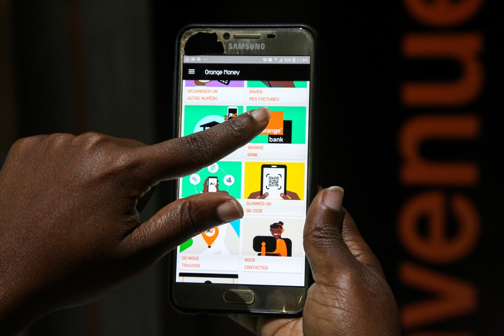 A woman prepares to perform a financial transaction on her mobile phone at a bank of the French mobile operator Orange in Abidjan, Ivory Coast, September 18, 2020. Picture taken September 18, 2020. REUTERS/Macline Hien - RC258J9G2FJF