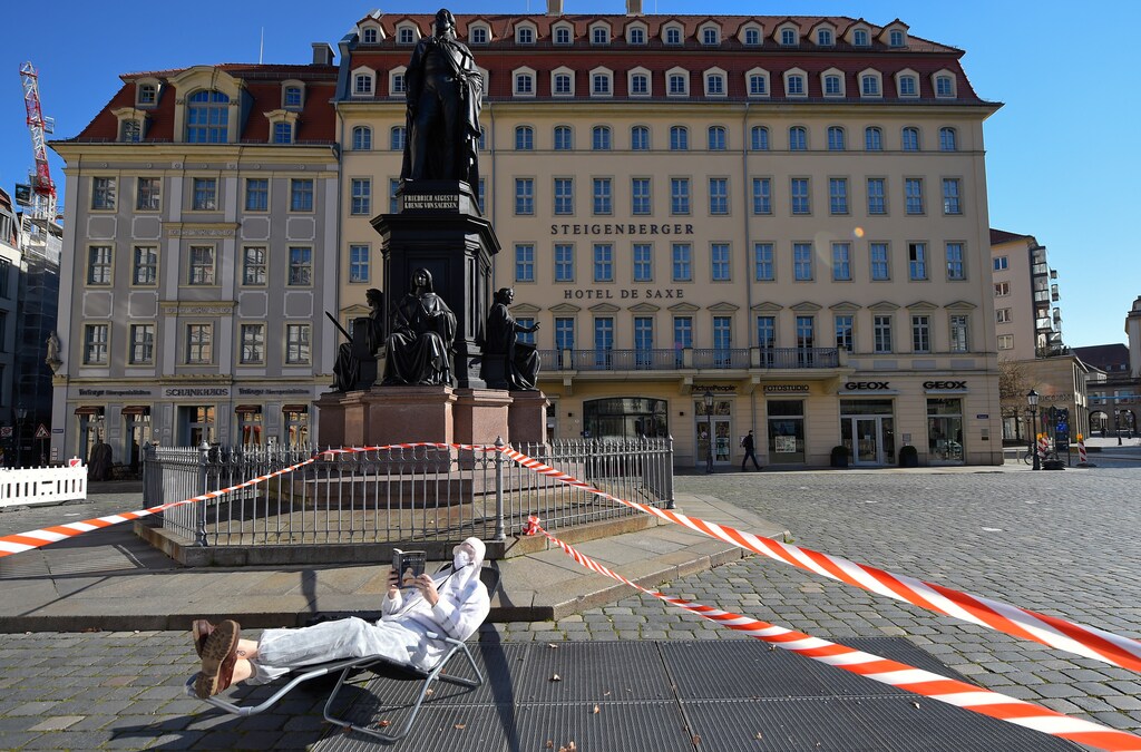 A man, wearing a protective mask, glasses and a suit is reading a book in the sun during a partial lockdown in Dresden, Germany, March 23, 2020, as the spread of the coronavirus disease (COVID-19) continues. REUTERS/Matthias Rietschel - UP1EG3N15H84Y