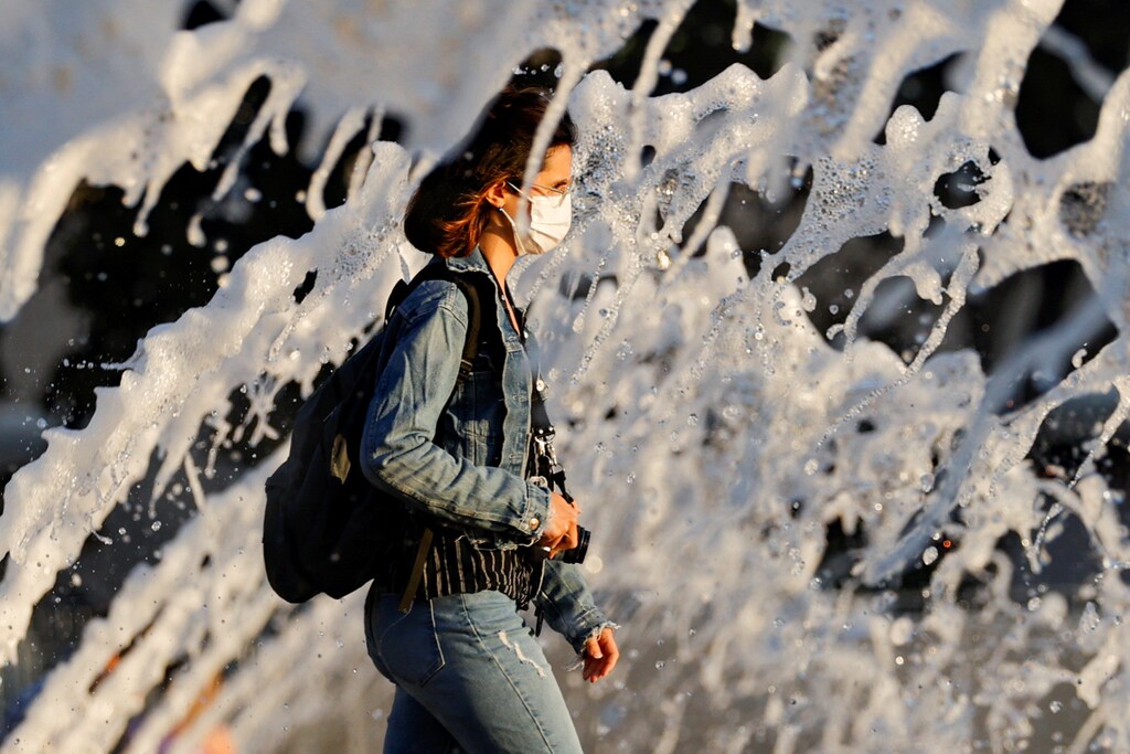 A woman wearing a face mask walks past a fountain amid the spread of the coronavirus disease (COVID-19), in San Diego, California, U.S., June 18, 2020. REUTERS/Mike Blake TPX IMAGES OF THE DAY - RC22CH94JQX4