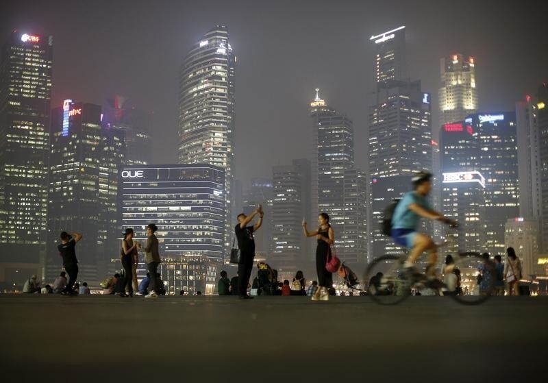 People take photos with the skyline of the central business district shrouded by haze in Singapore September 10, 2015. REUTERS/Edgar Su