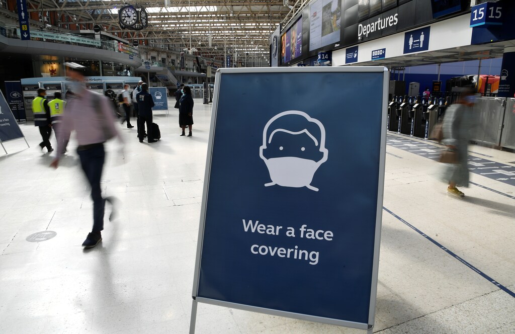 Workers wearing face-masks walk past an information board as they travel through the Waterloo Station during the morning rush hour following the coronavirus disease (COVID-19) outbreak, in London, Britain, July 6, 2020. REUTERS/Toby Melville - RC2KNH91A29I