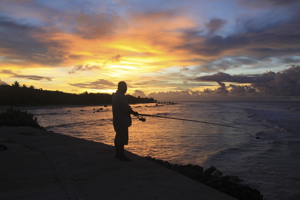 A fisherman is pictured at sunset at the northern end of the airport runway on the small nation island of Nauru, April 15, 2010. Australia has flooded Nauru with money since 2012, when the island became a key plank in its controversial policy of dealing with asylum seekers. Nauru hosts a detention centre able to hold 1,500 men, women and children from the Middle East, Africa and Asia who have been sent there after trying to get to Australia in rickety boats, usually from Indonesia. Picture taken April 15, 2010. To match Insight AUSTRALIA-NAURU/ REUTERS/Rod Henshaw