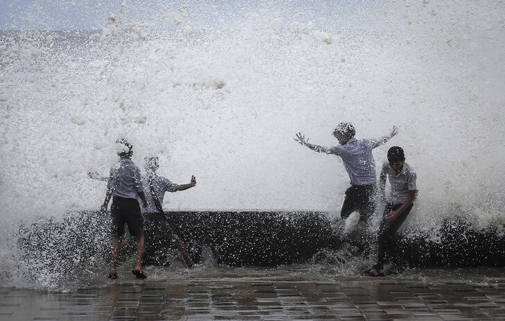 School boys get drenched in a large wave during high tide at a sea front in Mumbai July 14, 2014. Weak rainfall in India since the start June, when the monsoon season began, has raised concerns of a first drought in five years, although weather experts are hopeful rains will revive in the next week. REUTERS/Danish Siddiqui (INDIA - Tags: SOCIETY ENVIRONMENT TPX IMAGES OF THE DAY)