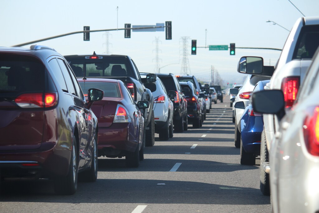 A line of cars waiting at a set of green traffic lights.