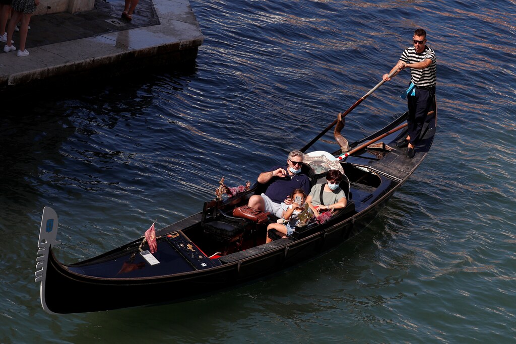 Tourists wear protective face masks as they take a gondola ride near Rialto bridge following the outbreak of the coronavirus disease (COVID-19) in Venice, Italy, September 9, 2020.