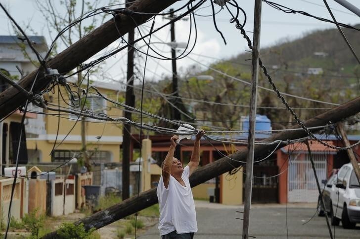 A resident uses a plastic bag to move downed power cables so he can drive underneath them in a neighborhood following Hurricane Maria in Ceiba, Puerto Rico, October 4, 2017. Picture taken October 4, 2017. REUTERS/Lucas Jackson