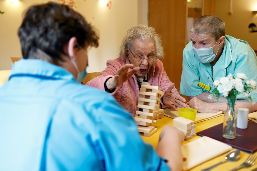 An elderly women plays a game in a care home setting