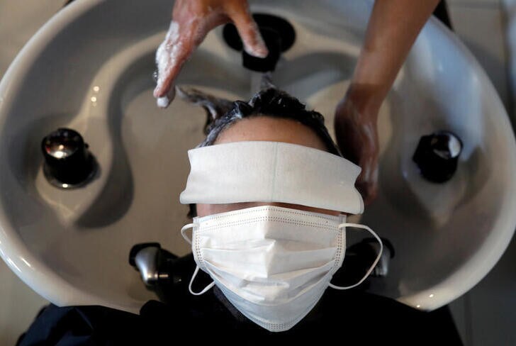 Customer Natsuki Suda, wearing a protective mask to prevent infection, receives hair treatment from the owner of hair salon Pinch, Akihiro Yoshida, following the coronavirus disease (COVID-19) outbreak, in Tokyo, Japan, April 28, 2020. According to Yoshida, the revenue of his salon in April falls less than 50 percent of the usual season and now it accepts one customer at a time by appointment only as a measurement for preventing the infection. REUTERS/Kim Kyung-Hoon TPX IMAGES OF THE DAY