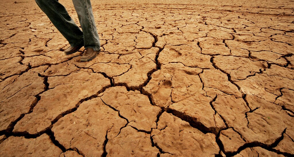 A Pakistani walks as cracks are seen at Rawal Lake in Islamabad, which is the main source of water supply to Rawalpindi, May 8, 2006. Pakistan is facing a possible drought as there are no signs of any significant rains in the country in the next couple of months, the country's top weatherman warned on Monday. REUTERS/Mian Khursheed - GM1DSOEYPJAA