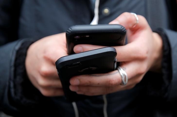 A woman uses her cell phones in Manhattan, New York, U.S., January 30, 2018. REUTERS/Andrew Kelly
