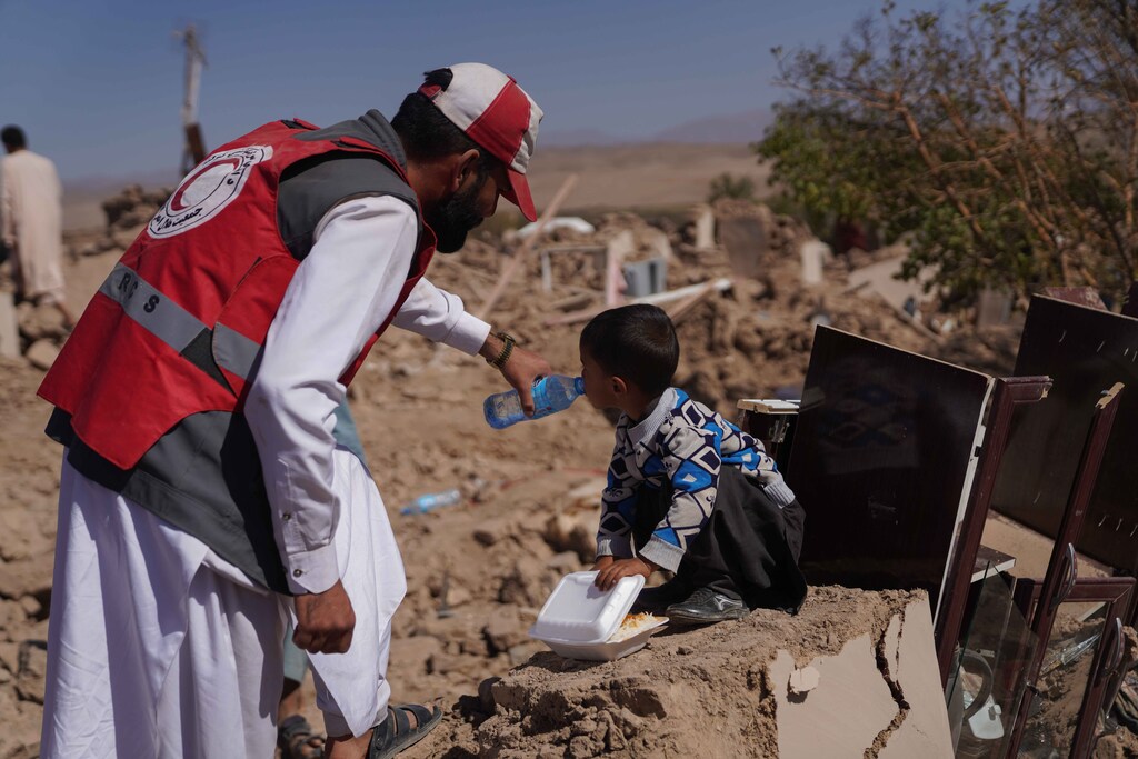 An IFRC aid worker give water to a child in Afghanistan.