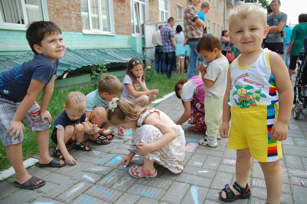 People gather outside an office of the Russian federal migration service, with children seen playing in the foreground, in Belgorod, June 9, 2014. People, many of whom claimed they had recently arrived from Ukraine and called themselves Ukrainian citizens, came to the office of the service to receive the refugee status, according to those present. The Russian Belgorod region shares borders with districts of eastern Ukraine. REUTERS/Vladimir Kornev (RUSSIA - Tags: POLITICS CIVIL UNREST SOCIETY IMMIGRATION CONFLICT) - RTR3SXWR