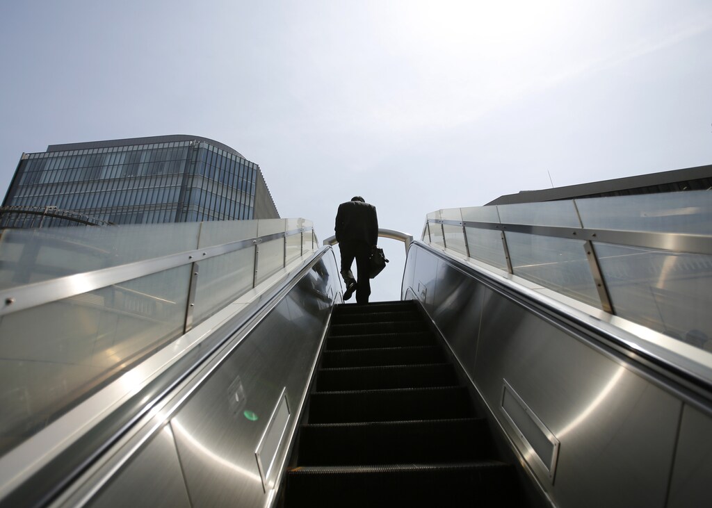 A businessman rides on an escalator in Tokyo's business district April 1, 2013. Japanese business sentiment improved in the first three months of 2013, a central bank survey showed, after Prime Minister Shinzo Abe's aggressive monetary and fiscal policy prescriptions helped to weaken the yen and bolster share prices. REUTERS/Toru Hanai (JAPAN - Tags: POLITICS BUSINESS) - GM1E94112JU01