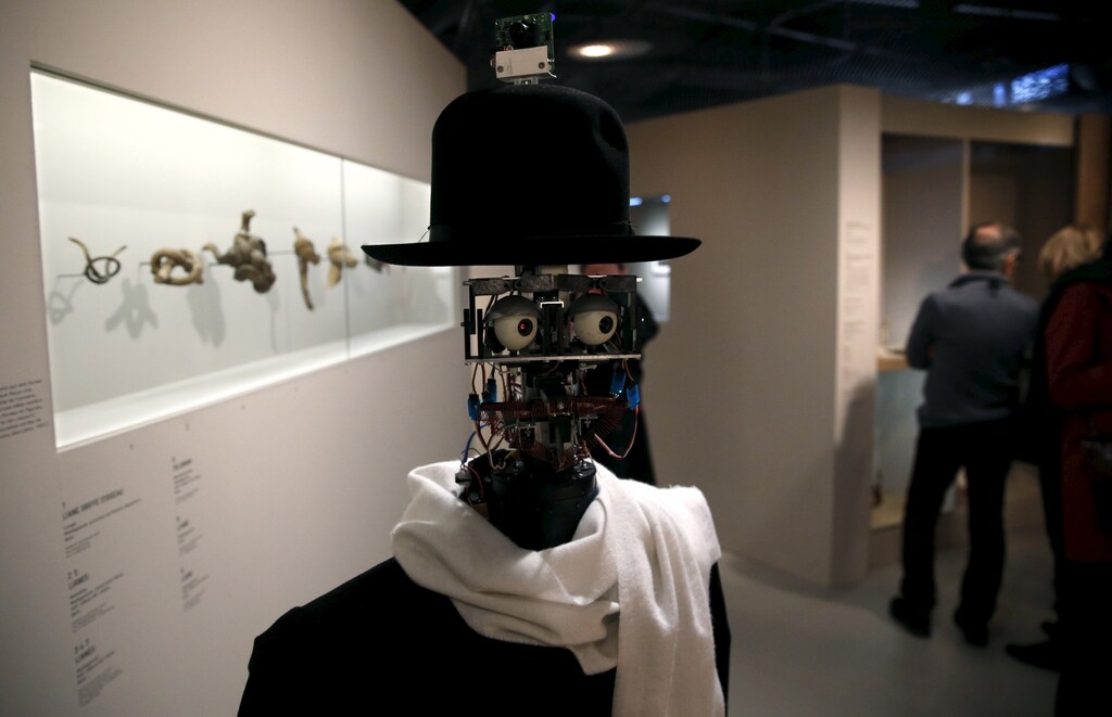The Berenson robot strolls among visitors during the exhibition "Persona : Oddly Human" at the Quai Branly museum in Paris, France, February 23, 2016. The Berenson robot, developed in France in 2011, is the brainchild of anthropologist Denis Vidal and robotics engineer Philippe Gaussier. Its programming allows it to record reactions of museum visitors to certain pieces of art and then use the data to develop its own unique taste, which allows "Berenson" to judge whether or not it likes a certain work of art within an exhibition. Picture taken February 23, 2016. REUTERS/Philippe Wojazer TPX IMAGES OF THE DAY - RTX28DUZ