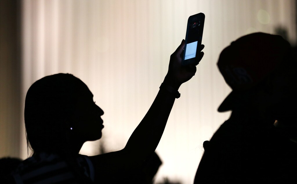 A protester uses her phone to make a video of the proceedings during another night of protests over the police shooting of Keith Scott in Charlotte, North Carolina, U.S. September 24, 2016. REUTERS/Mike Blake - HT1EC9P09K0XC