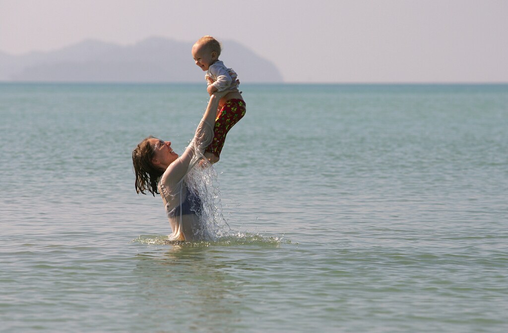 Veronika Areskoug from Uppsala, Sweden, plays with her 15-month-old daughter, Alfdis, in the calm waters of Khao Lak, Thailand, nearly 110 km (68 miles) north of the resort island of Phuket December 24, 2005. The December 26, 2004 tsunami killed 5,395 people, including many foreign tourists, and wiped out 47 villages along the country's Andaman Sea coastline. REUTERS/Adrees Latif - RP2DSFIVVDAA