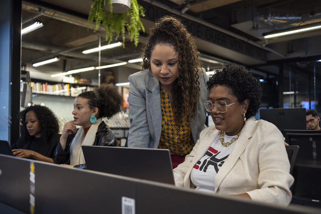 Mujeres en Brasil en una oficina frente a una computadora. La economía social en acción: El Fundo Agbara es el primer fondo filantrópico creado y gestionado por - y para - mujeres negras empresarias de Brasil.