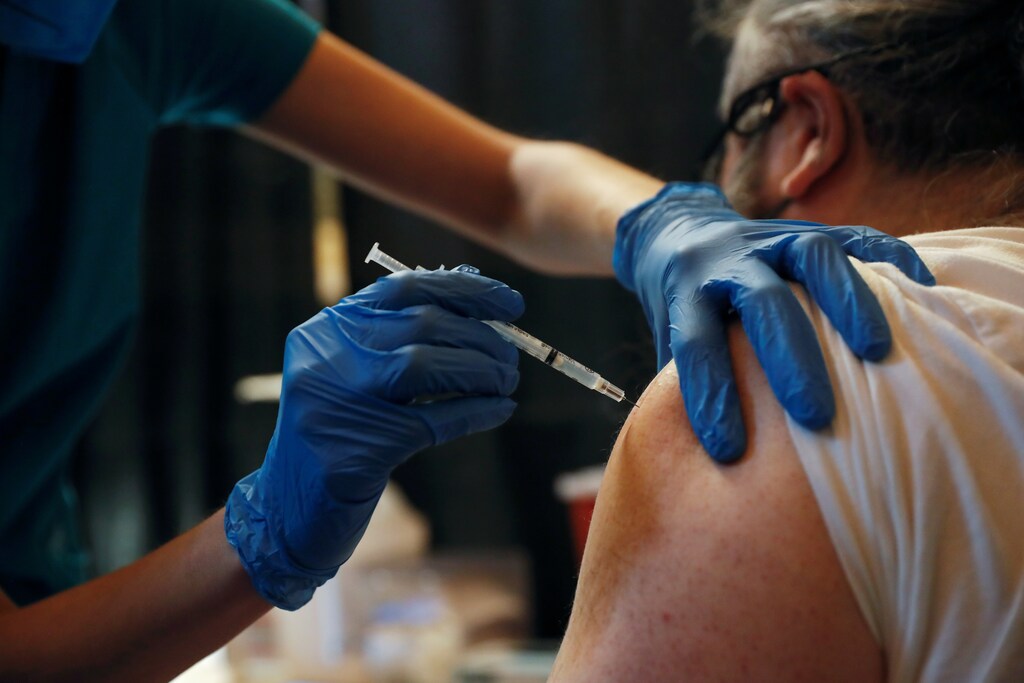 a picture of a medical worker injecting a covid vaccine
