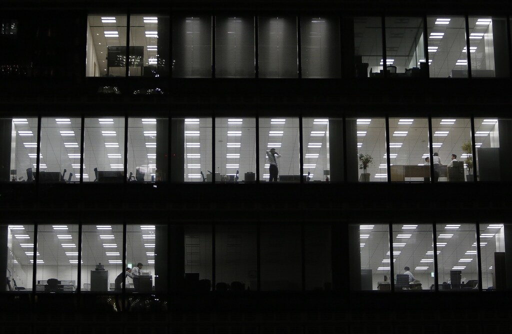 A man using his mobile phone stands near a glass window at a building at a Tokyo's business district March 18, 2015. Japanese blue-chip firms announced wage hikes that topped increases last year, but overall pay raises across corporate Japan are not expected to offset higher costs of living or be enough to drive a sustainable economic recovery. REUTERS/Yuya Shino (JAPAN - Tags: BUSINESS EMPLOYMENT) - RTR4TUDD