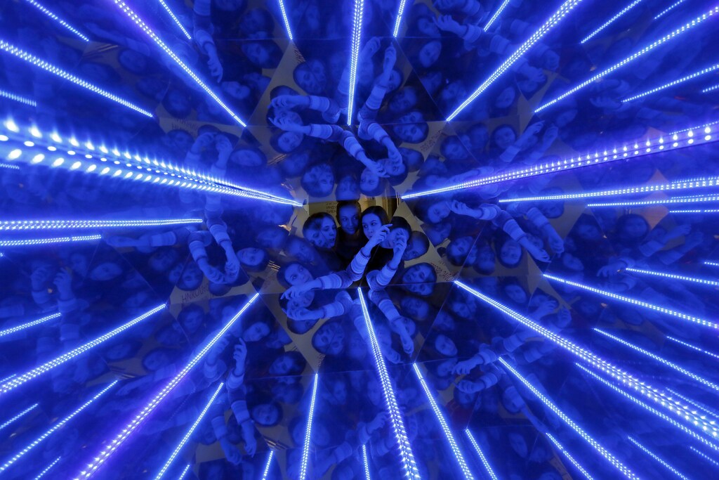 Three women are seen through a giant kaleidoscope as they look inside, as the exhibit is on display to demonstrate the geometric effect of filling space with equal triangles at the "Newton Park" interactive museum of science, during preparations for a performance for school children dedicated to the Russian Day of Science at the Museum Centre in Krasnoyarsk, Siberia, February 4, 2015. A group of young engineers, scientists and researchers, who specialize in chemistry, applied mathematics and physics, founded an interactive museum of science to conduct experiments aimed at the popularization of the exact sciences for pupils and their parents. REUTERS/Ilya Naymushin (RUSSIA - Tags: SCIENCE TECHNOLOGY EDUCATION ANNIVERSARY SOCIETY) - RTR4O7HW