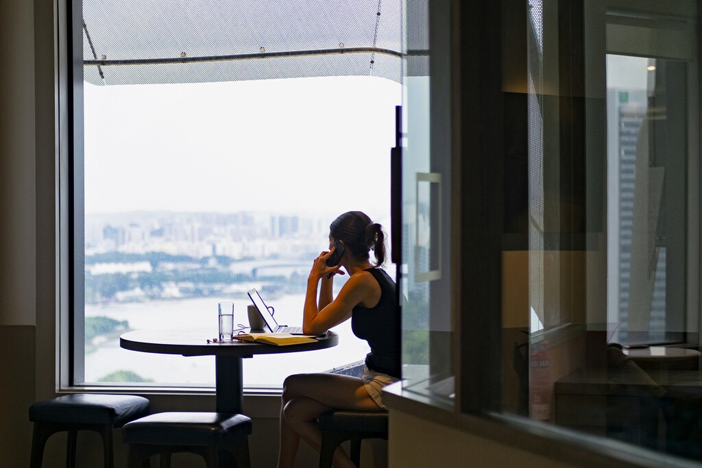 A woman answers a call while looking out the window in co-working space The Great Room's Centennial Tower location in Singapore, July 2, 2019. Picture taken July 2, 2019. REUTERS/Loriene Perera - RC122659CFA0