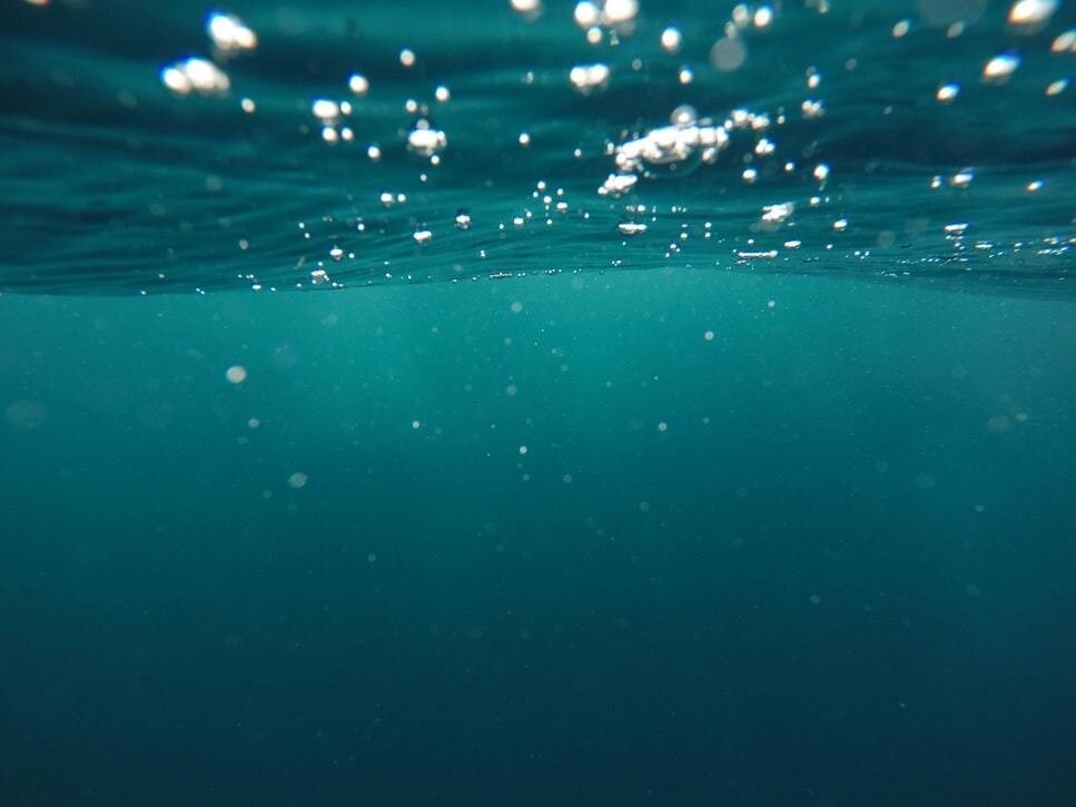 A photo of the ocean, with light streaming in from above.