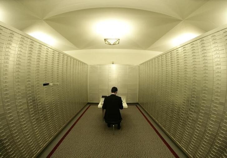 An employee sits amongst safe boxes before the public opening of the safe room of the Zuercher Kantonalbank (ZKB) at the Bahnhofstrasse in Zurich January 14, 2009. REUTERS/Christian Hartmann (SWITZERLAND)