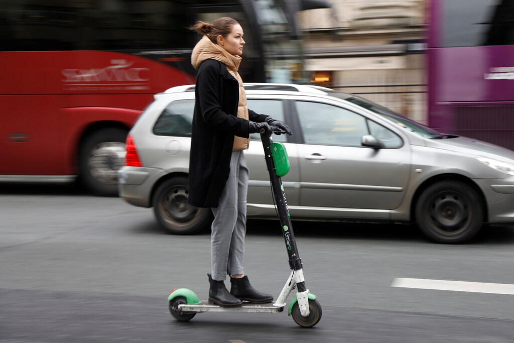 Una mujer monta un scooter eléctrico sin muelle o una "trotineta" Lime-S del servicio de bicicletas compartidas Lime, con sede en California, en una calle de París, Francia, 2019.