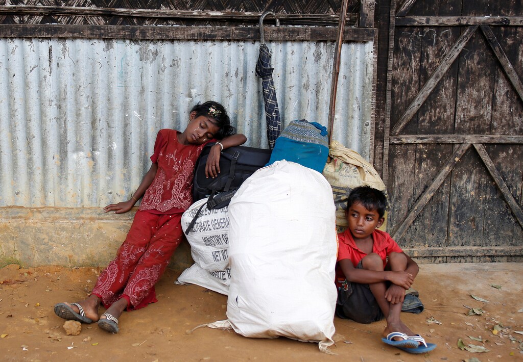 Exhausted Rohingya refugee siblings wait for their father, who went to check the status of their shelter at Kutupalong refugee camp, Bangladesh