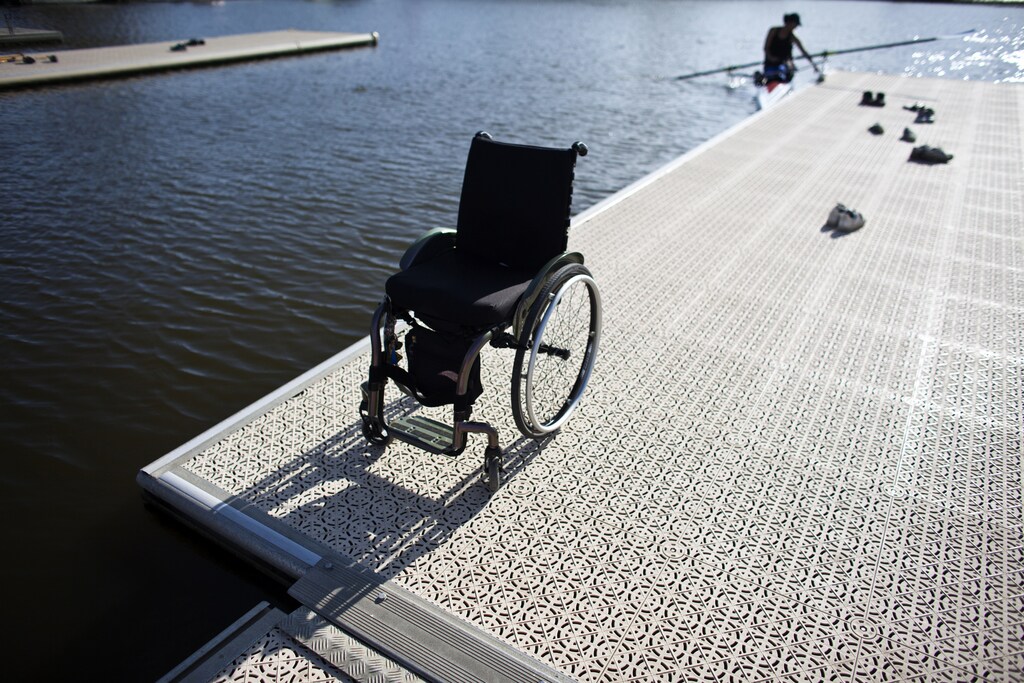 Israel's Moran Samuel's (seen at rear) wheelchair is seen as she returns to the platform at the end of a training session at the Yarkon stream in Tel Aviv May 21, 2012. Previously a professional basketball player in a national Israeli league Moran become partially paralyzed over night as a result of a blood clot in her spine, now Moran will represent the Israeli rowing team in the upcoming 2012 Paralympic Games in London. Picture taken May 21, 2012. REUTERS/ Nir Elias (ISRAEL - Tags: SPORT OLYMPICS ROWING) - GM1E86R06AB01
