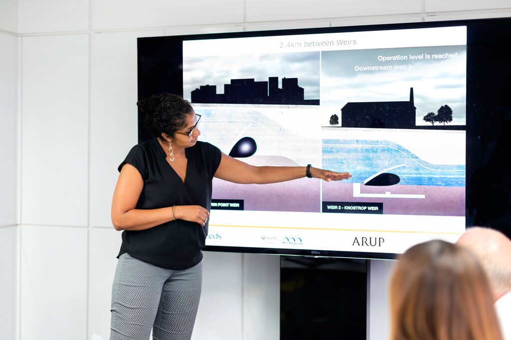 Female civil engineer presents designs to colleagues.