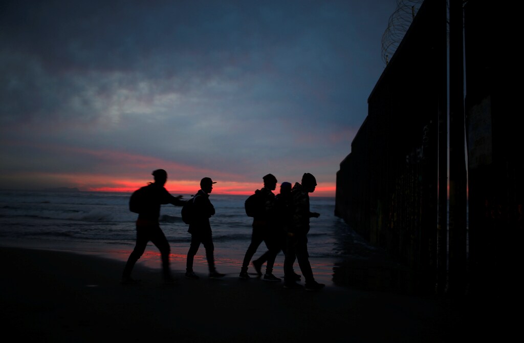 Migrants from Honduras, part of a caravan of thousands from Central America trying to reach the United States, walk next to the border fence as they prepare to cross it illegally, in Tijuana, Mexico, December 14, 2018. REUTERS/Mohammed Salem - RC1629312540