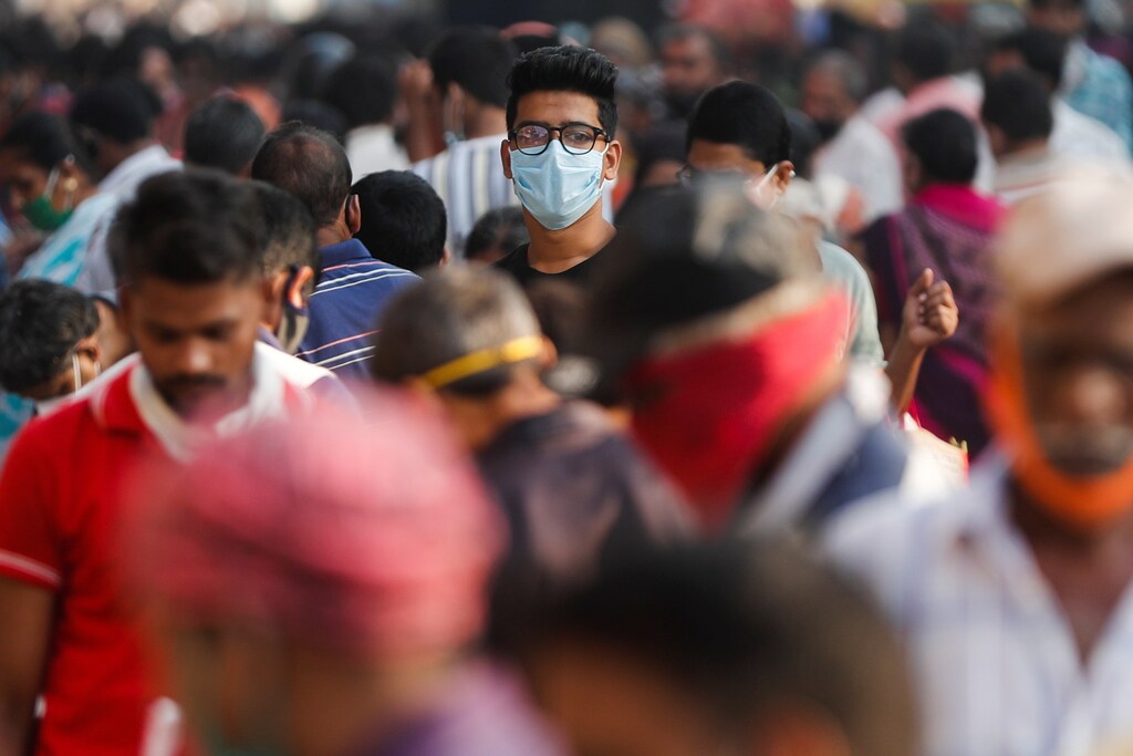 A man wearing a protective mask is seen among people at a crowded market amidst the spread of the coronavirus disease (COVID-19) in Mumbai, India, October 29, 2020. REUTERS/Francis Mascarenhas - RC24SJ9M7M7C