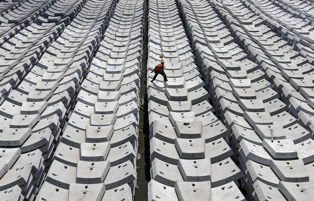 A worker walks over giant pieces of concrete that will be used to make tunnels for the metro railway, at a casting yard in the southern Indian city of Chennai November 20, 2013. India is likely to achieve an economic growth of between 5-5.5 percent in this fiscal year, the finance minister said last week, despite wide expectations of growth slipping below 5 percent by private economists. REUTERS/Babu (INDIA - Tags: BUSINESS CONSTRUCTION TRANSPORT) - GM1E9BK1FWL01