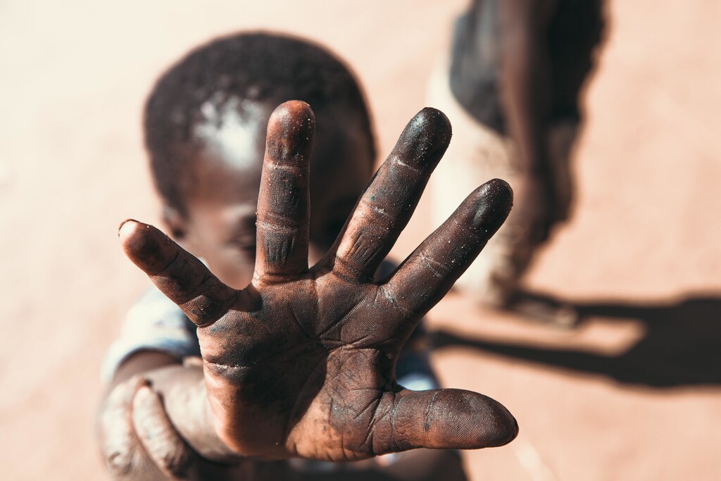 A child in Africa holds his hand up to the camera.