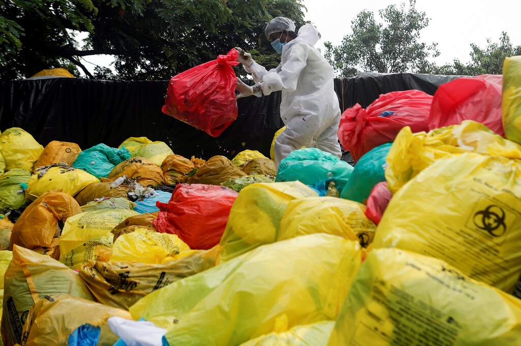 A man in personal protective equipment (PPE) clears bags filled with medical waste at a hospital, amidst the spread of the coronavirus disease.