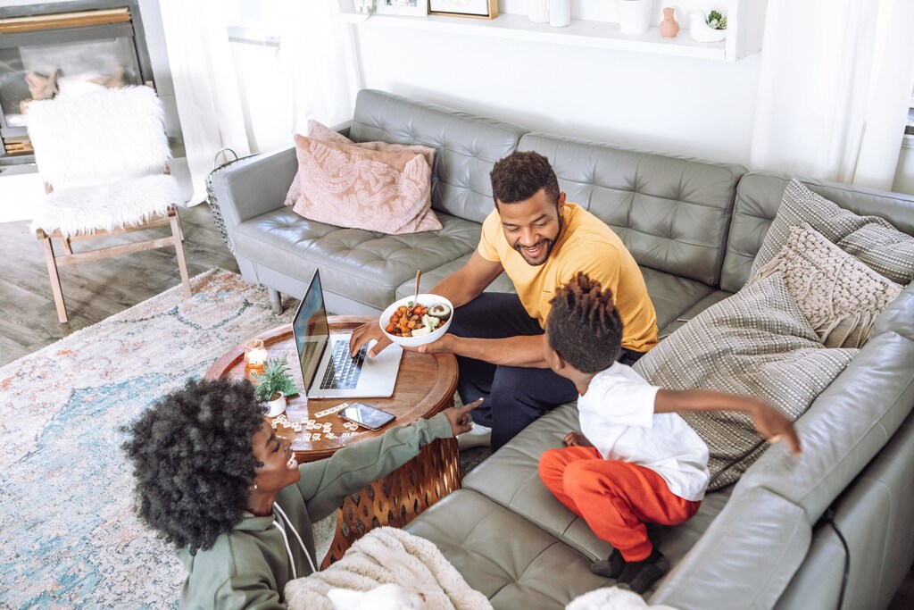 a family sits on their sofa eating dinner
