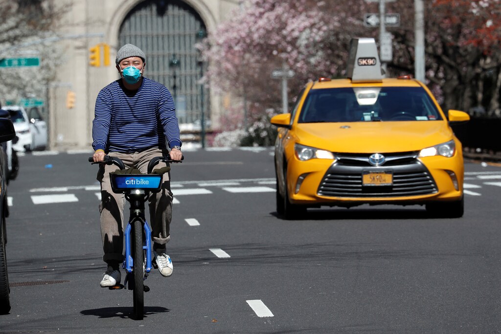 A man wearing a protective mask rides a bicycle on Park Avenue in midtown Manhattan during the outbreak of the coronavirus disease (COVID-19) in New York City, New York, U.S., March 24, 2020. REUTERS/Mike Segar - RC2IQF9LJ6YW