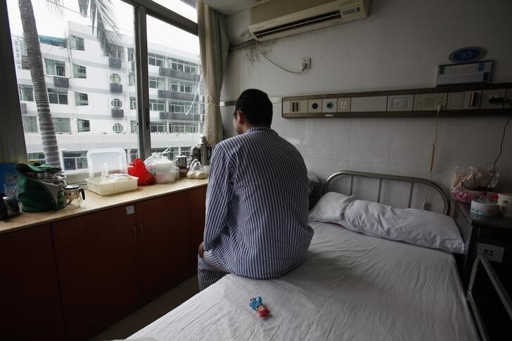 Zhang Tingzhen looks out of the window while sitting beside a doll given by his mother to play with at a Shenzhen hospital in southern China September 26, 2012. Apple Inc's largest contract manufacturer has been pushing for a Chinese worker left brain-damaged in a factory accident to be removed from hospital in a case that throws a harsh new spotlight on labour rights in China. Zhang Tingzhen, 26, an employee of Taiwan firm Foxconn, had nearly half his brain surgically removed after surviving an electric shock at a plant in southern China a year ago. He remains in hospital under close observation by doctors, unable to speak or walk properly. However, Foxconn, which is paying Zhang's hospital bills, has been sending telephone text messages to his family since July, demanding they remove him from hospital and threatening to cut off funding for his treatment - a move the firm says would be justified under Chinese labour law.Picture taken September 26, 2012. REUTERS/Stringer (CHINA - Tags: HEALTH BUSINESS EMPLOYMENT)