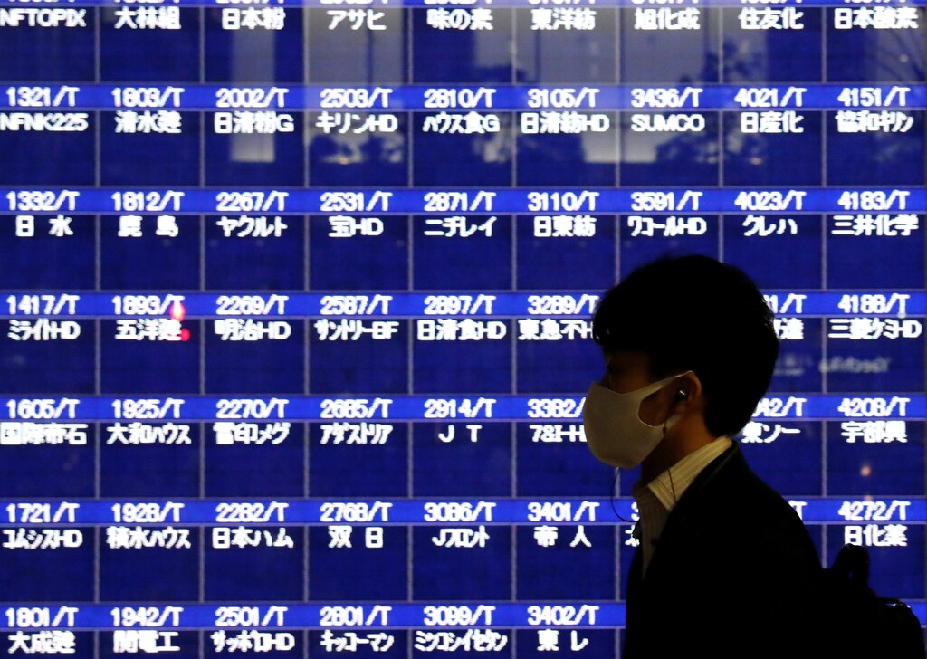 A passerby wearing a protective mask is silhouetted in front of a screen of blank prices on a stock quotation board after Tokyo Stock Exchange temporarily suspended all trading due to system problems, amid the coronavirus disease (COVID-19) pandemic, in Tokyo, Japan October 1, 2020. REUTERS/Issei Kato - RC2M9J9BFFEH