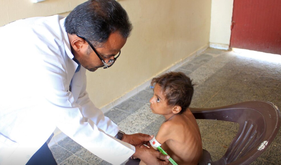 Hassan Merzam Muhammad pictured receiving medical attention by a doctor due to being severely malnourished.