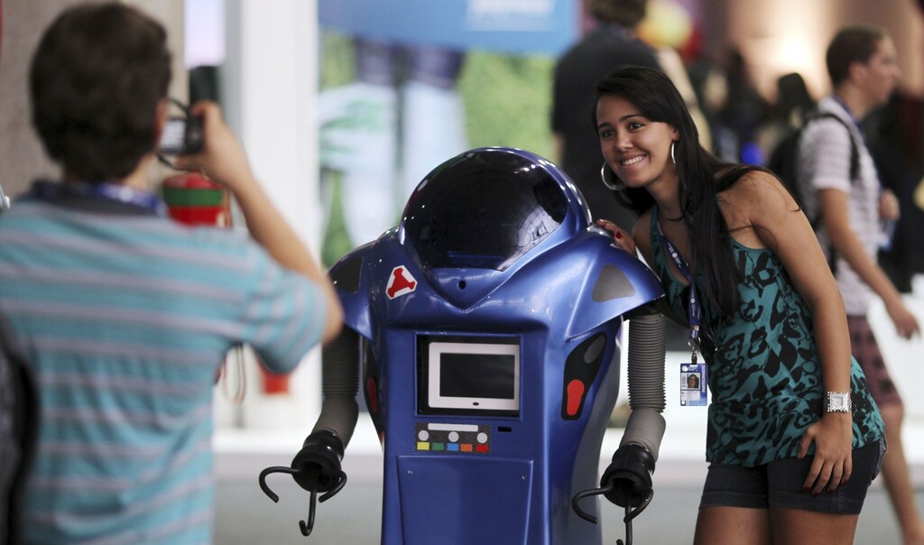 A participant poses next to a robot during a "Campus Party" Internet users gathering in Sao Paulo January 18, 2011.