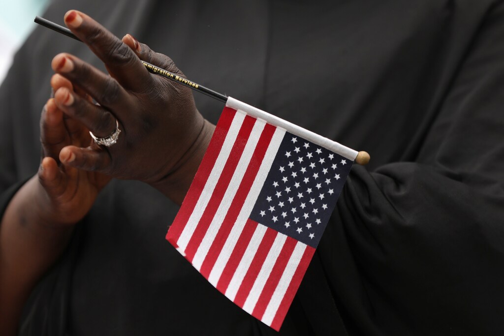 Fatoumata Jangana, from Gambia, claps holding an American flag during a naturalization ceremony at Franklin D. Roosevelt Four Freedoms Park, Roosevelt Island in New York City, U.S., June 16, 2017. REUTERS/Shannon Stapleton - RTS17EP5