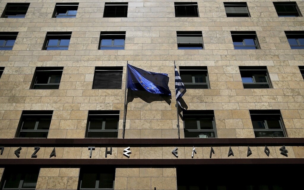 A European Union flag (L) flutters next to a Greek flag on the facade of the Bank of Greece headquarters in Athens April 14, 2015. Greece denied on Monday a report by the Financial Times that it was preparing for a debt default if it did not reach a deal with its creditors by the end of the month and said the negotiations were proceeding "swiftly" towards a solution.