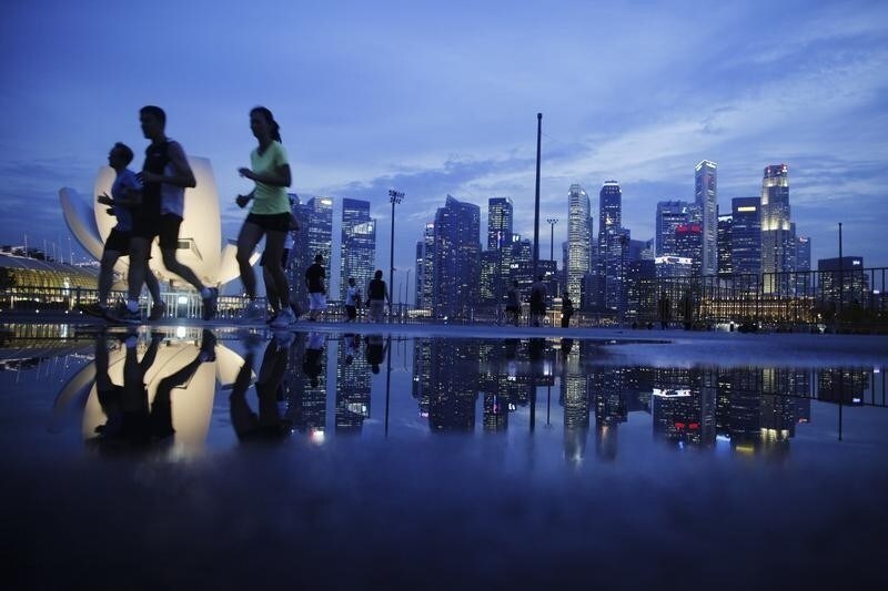 Joggers run past as the skyline of Singapore's financial district is seen in the background April 21, 2014