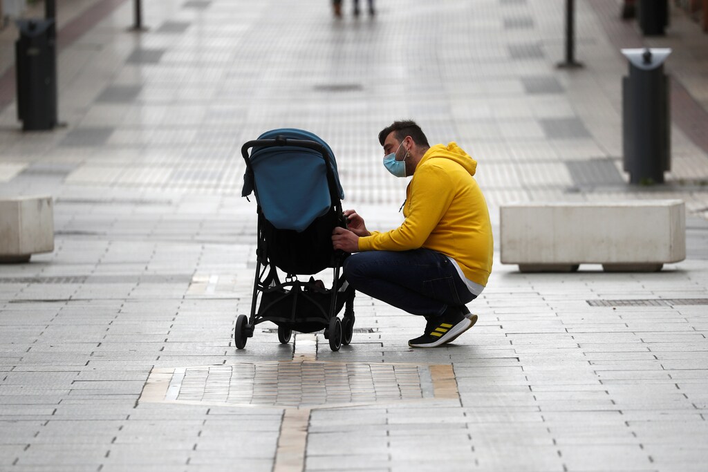 A man talks to his daughter sitting on a baby carriage in the empty La Bola street, after restrictions were partially lifted for children for the first time in six weeks, during the coronavirus disease (COVID-19) outbreak in Ronda, Spain, April 26, 2020. REUTERS/Jon Nazca - RC2ECG983NWG