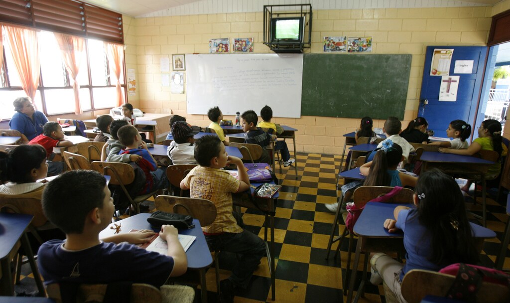 Schoolchildren are seen watching television, with their teachers, inside a school in Costa Rica.